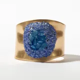 Brazalete rígido dorado con aplicación de piedras azules.