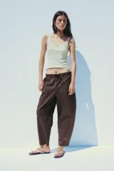 Pantalón marrón tipo barrel, de tiro medio con cintura elástica ajustable con lazada, bolsillos laterales y falsos bolsillos de vivo en la espalda.