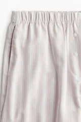 Pantalón de pijama de algodón suave con rayas verticales, corte relajado, tiro bajo, cintura elástica, cierre decorativo con botones y bolsillos laterales.
