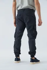 Pantalón cargo gris oscuro, corte slim, con cierre de botón y cremallera, trabillas para cinturón, bolsillos cargo con botón y puños ajustados.