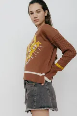 Buzo azul marino tejido en jacquard con diseño de frutas y verduras. Tiene mangas tejidas en ochos, bordado en la espalda y puños con agujerito para el dedo.