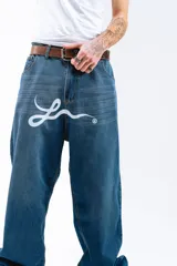 Pantalón de jean azul desgastado, corte mega baggy, con estampa serigrafiada en la pierna y botones personalizados.