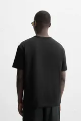 Camiseta negra de algodón de corte regular, con cuello redondo con ribete doble y mangas cortas.