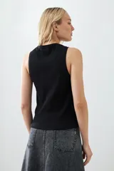 Musculosa color crudo de tejido de punto canalé, sin mangas y cuello redondo.