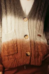 Cárdigan tejido a rayas horizontales con degradé de color, con cuello en V, mangas largas y cierre frontal con botones de madera.