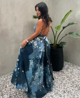 Vestido largo de tela fluida, color verde esmeralda con estampado abstracto en tonos turquesa y detalles dorados. Diseño asimétrico con un solo tirante tejido en el hombro.