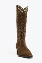 Bota alta de cuero color marrón con bordados en color blanco y negro.