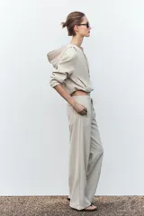 Pantalón de tiro alto color hueso, con bolsillos delanteros y traseros, cintura elástica ajustable con cordones y corte ancho.