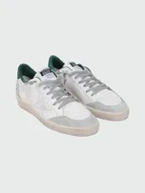 Championes Golden Goose modelo Ball Star, color blanco con detalles en gris y verde. Presentan una estrella plateada en el lateral, puntera y talón en gamuza gris, y detalle verde en el talón. Cordones grises y suela color crema con efecto envejecido.