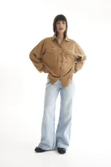Camisa marrón de pana, corte oversize, con cuello camisero, cierre frontal con botones, mangas largas y dos bolsillos de parche en el pecho.