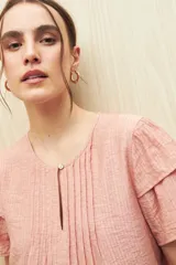 Blusa blanca de tela liviana con mangas cortas con volados y botón de nácar.