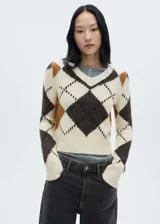 Sweater de punto color crema con diseño de rombos en marrón, gris y ocre. Tiene cuello en V y mangas largas con terminaciones en canalé.