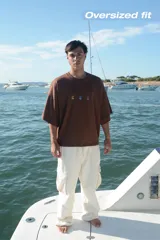 Camiseta celeste de manga corta con cuello redondo y estampado frontal de tres recipientes con cereales. En la parte trasera tiene un estampado grande con el texto "iUTTAi STARS" y un plato con cereales.