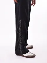 Pantalón de jogging negro con cintura elástica ajustable con cordón, bolsillos laterales y detalle de encaje en los laterales.