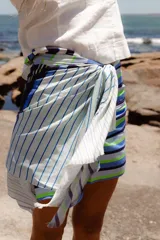 Pareo rectangular de viscosa con estampado de flores rojas sobre fondo borgoña y borde inferior con rayas verticales rojas, amarillas y blancas.