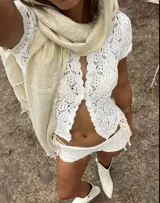 Conjunto de tejido crochet color blanco, compuesto por un cárdigan con botones y shorts.