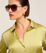 Camisa blanca de satén con cuello inglés, manga larga y cierre frontal con botones.