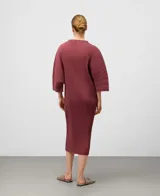 Vestido midi color vino tinto con cuello alto y mangas anchas de tres cuartos. La tela presenta un plisado vertical en todo el cuerpo, con un patrón de textura en relieve en la parte inferior.