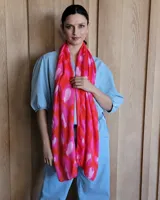 Chalina rectangular de tela fina con estampado abstracto en tonos fucsia, rosa y naranja.