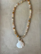 Collar largo de cuentas de piedras semipreciosas en tonos tierra, con dijes de conchas marinas.