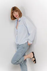 Camisa color crema de manga larga con cuello camisero y detalles de encaje en el escote. Se ata en la parte delantera.