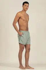 Short de baño gris claro, con cintura elástica ajustable, dos bolsillos laterales y uno trasero con cierre. Tiene suspensor de malla fina hipoalergénico y protección UV 50.