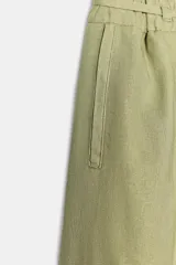 Pantalón ancho color verde oliva confeccionado en lino. Tiro alto con cintura elástica ajustable con cordón y pinzas delanteras. Presenta bolsillos laterales y traseros. Incluye cinturón de la misma tela con apliques metálicos.