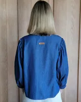 Camisa de mangas largas abullonadas con puños elásticos, cuello redondo y cierre frontal con botones.