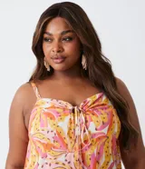 Vestido corto con tirantes finos, escote en V con lazo ajustable y estampado de bananas en tonos rosa, naranja y amarillo.