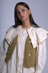 Chaleco tejido color crema con escote en V y cierre frontal con lazos. Presenta bordados de flores en tonos naranja, verde y blanco.