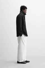 Parka negra de algodón con cuello solapa de cuero sintético, corte recto, acolchada y con cierre frontal de botones.
