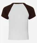 Remera ajustada de algodón con mangas cortas estilo raglán en color marrón oscuro y cuerpo blanco. Presenta un estampado central con el texto "MONACO 1987 EUROPE" en color marrón.