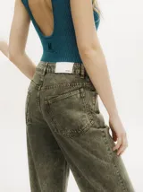 Pantalón de denim verde oliva con efecto gastado, corte recto, tiro medio y botones metálicos en el lateral inferior.