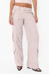 Pantalón cargo color arena de corte recto y tiro bajo, con recortes y presillas dobles en la cintura. Tiene acceso mediante cierre de nylon y botón personalizado, seis bolsillos laterales y dos en la espalda con tapa y botón snap a presión.