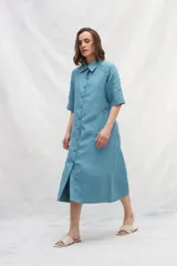 Vestido camisero celeste de lino con abotonadura frontal completa, manga ranglan, bolsillos laterales y volante en el ruedo.