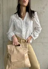 Camisa blanca de algodón con bordado inglés, cuello en V y mangas largas abullonadas.