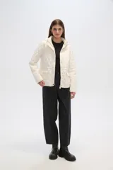 Campera blanca con diseño acolchado, cierre frontal con botones a presión y capucha desmontable.