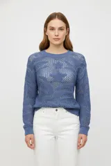 Sweater azul de punto calado, con cuello redondo y mangas largas. Diseño holgado y tejido traslúcido.
