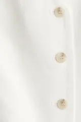 Chaleco de vestir blanco en mezcla de lino y viscosa con escote en V, botonadura frontal, trabilla ajustable en la espalda y forro interno.