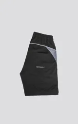 Bermuda negra con recortes blancos y grises, calce oversize, textil liviano, elástico en la cintura, cordón de ajuste, bolsillos delanteros y traseros.