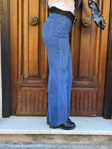 Pantalón de jean azul de corte recto y tiro alto, con cinturón de cuero negro con hebilla plateada.