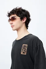 Remera negra de corte amplio con mangas cortas y cuello redondo. Presenta un pequeño estampado rectangular en el pecho y un estampado grande en la espalda con motivos japoneses.