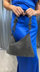 Cartera negra con strass plateados, forma triangular y asa corta con detalle de nudo.