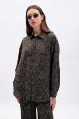 Camisa de manga larga, corte oversize, con cuello camisero y botones frontales. Estampado de patrón orgánico en color dorado sobre fondo negro.