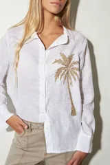 Camisa blanca de lino con bordado de una palmera en el pecho.