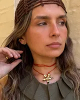 Collar artesanal con dije de flor plateada, realizado con hilo de seda natural teñido a mano.