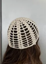 Gorro tipo casquete tejido a crochet color crema, con detalle de perla colgante en el centro.