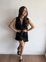 Vestido corto negro sin mangas de tela voile con cuello camisero y abotonadura frontal.