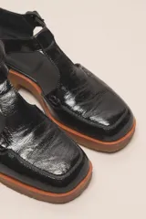 Zapato guillermina de cuero vacuno charol color negro, con suela de goma color marrón.