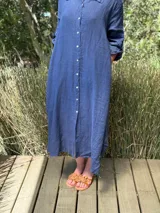 Vestido camisero amplio y largo de lino color azul, con botones de nácar, cuello camisero y bolsillos laterales.